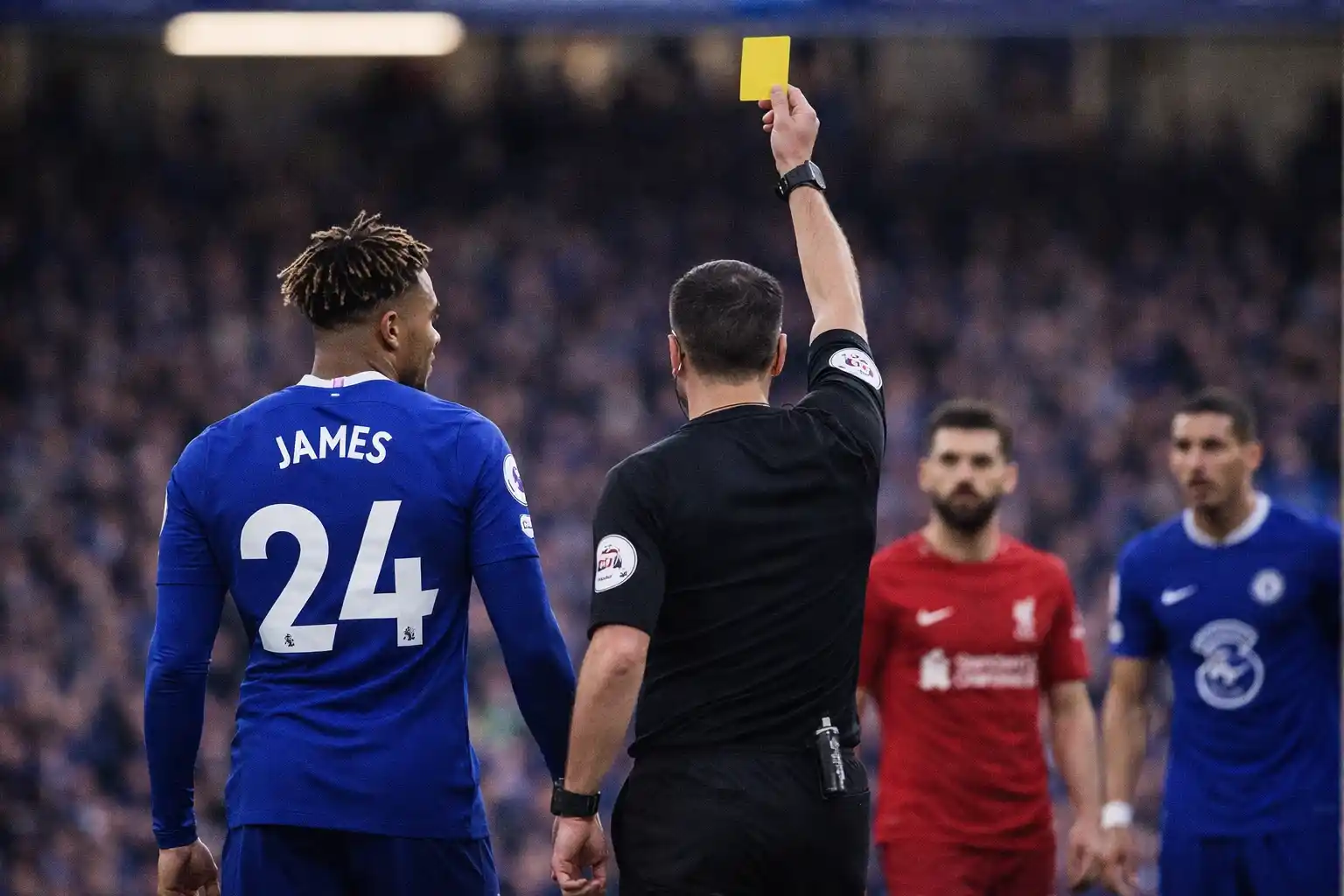 Referee holding up a yellow card during a Premier League match