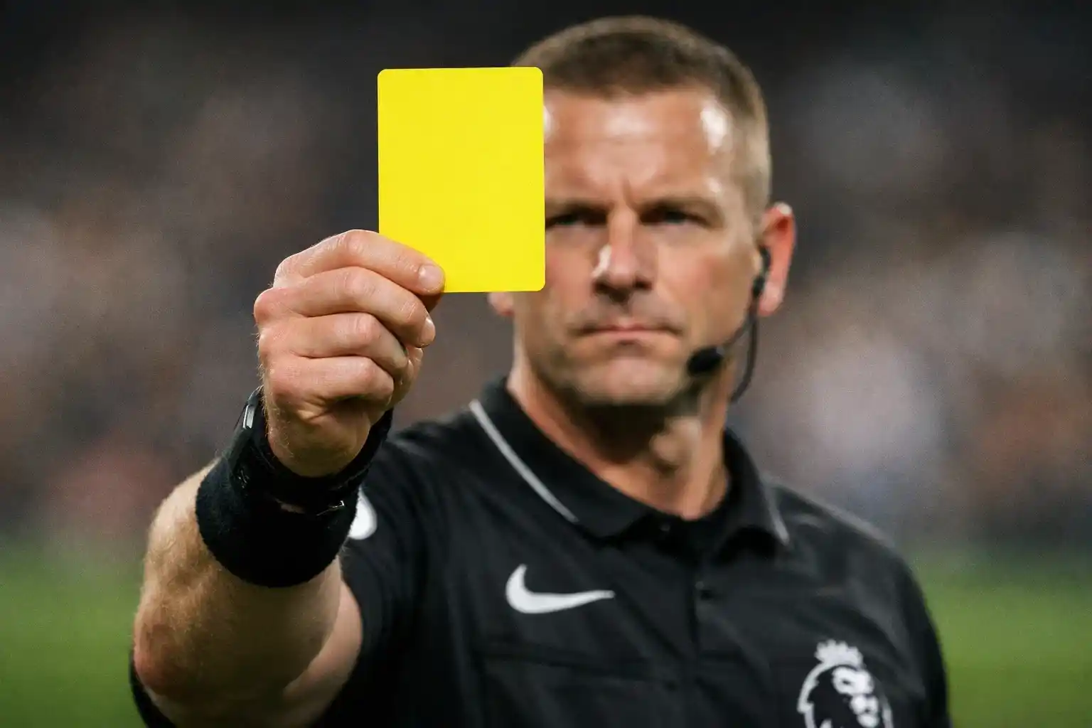 Close-up of a referee holding up a yellow card during a football match